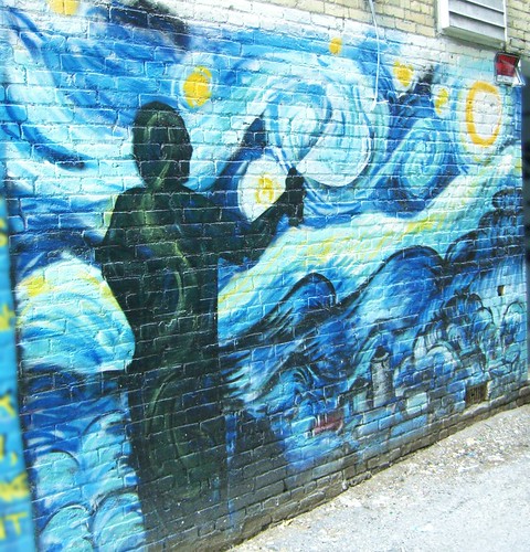 graffiti of stars painted on a brick wall; the painting also shows the silhouette of a person holding a spray can, creating the art.