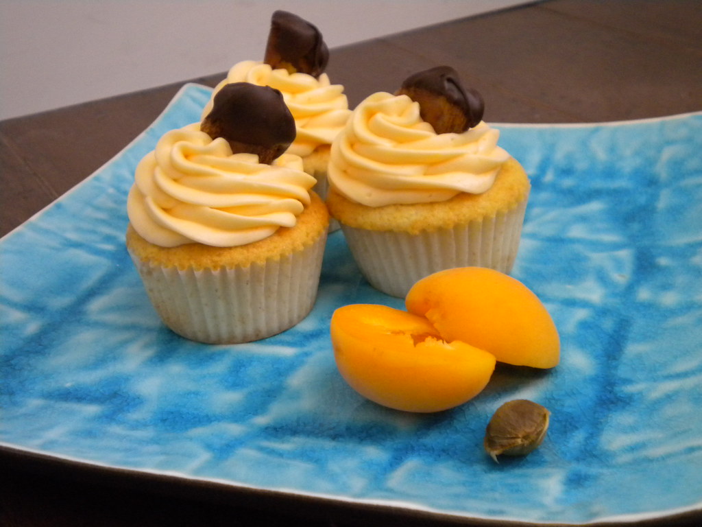 Vanilla cupcake with apricot filling, apricot cream cheese frosting, topped with a chocolate-dipped dried apricot