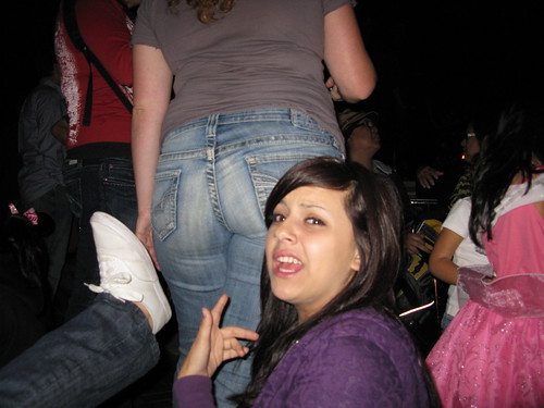 A jealous girl points at the back of a woman wearing jeans