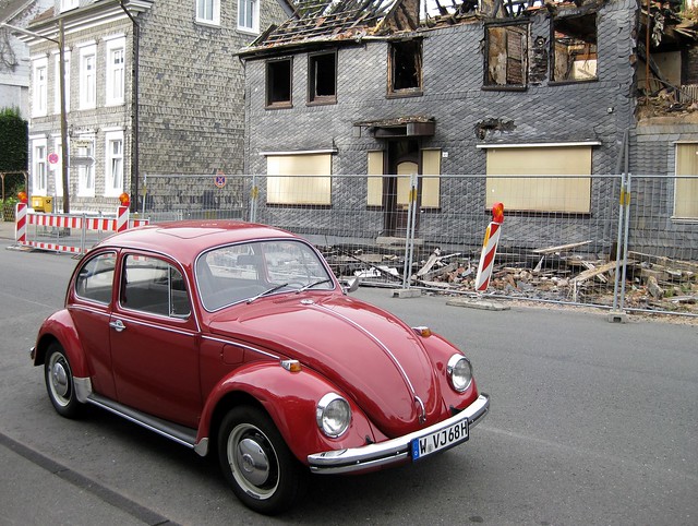 What we saw on our cycling tour: red Volkswagen beetle in front of burned house
