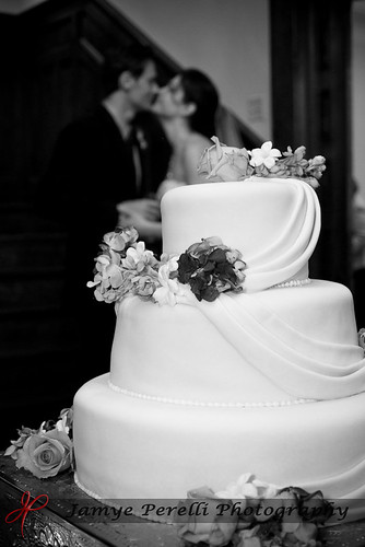 A beautiful wedding cake with a little kiss in the background