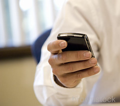 Corporate business man messaging using a blackberry pda cell phone. by Brownstock