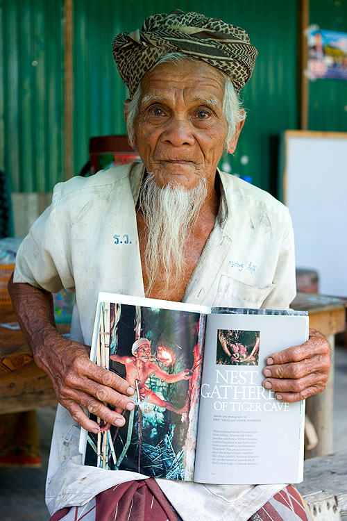 Sahat, a bird nest gatherer from Ko Yao Noi, Thailand, holds a copy of the National Geographic article that features him