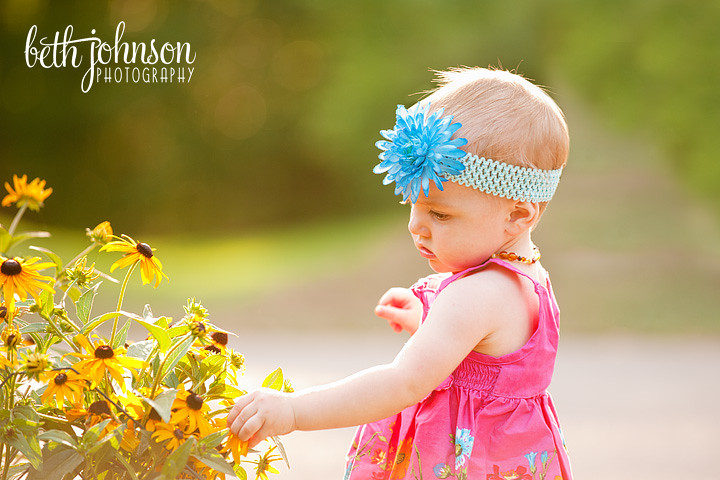 one year old baby girl in front of flowers