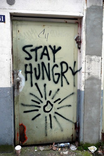 image of a door with black, spray-painted graffiti, "Stay Hungry"