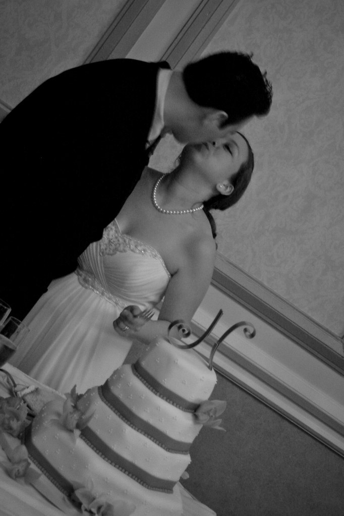 Sweet candid kiss moment during cake cutting at wedding reception