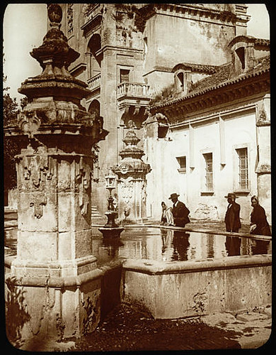 Lestrange. Fountain in the patio, Mosque of cordoue. Fountain in the foreground, characters, visible mosque partly the background.