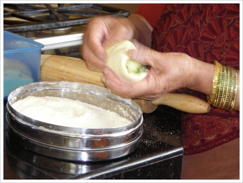 Champa folding the potato filling into the dough by you.
