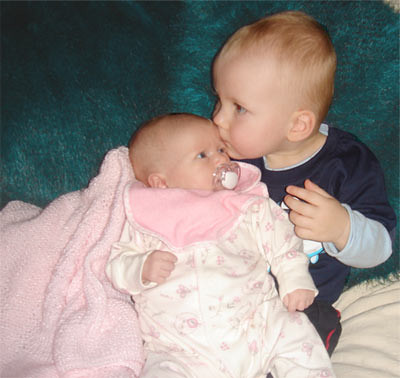 A young boy kisses his new born sister