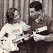 Carolyn Noble as Jim Atkinson tutors her with a guitar
