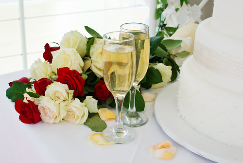 Bridal Bouquet of Roses With Wedding Reception Cake and Glasses of Champagne