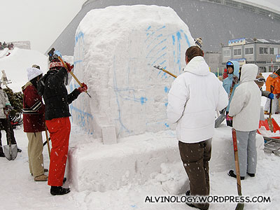 Snow sculpturing contestants slugging it out on their assigned block of snow