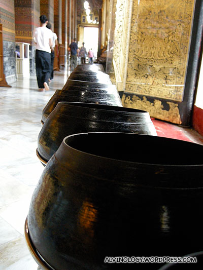 There are rows of alm bowls in front of the sleeping Buddha for making donations