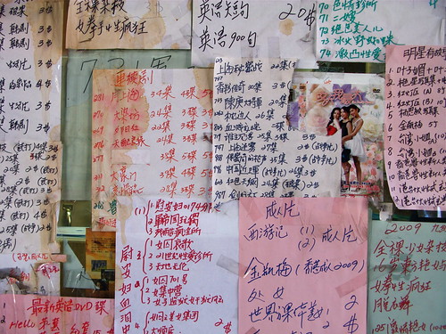 Lists of pirated DVDs posted on a storefront in Chinatown.