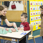 A student playing with preschool students