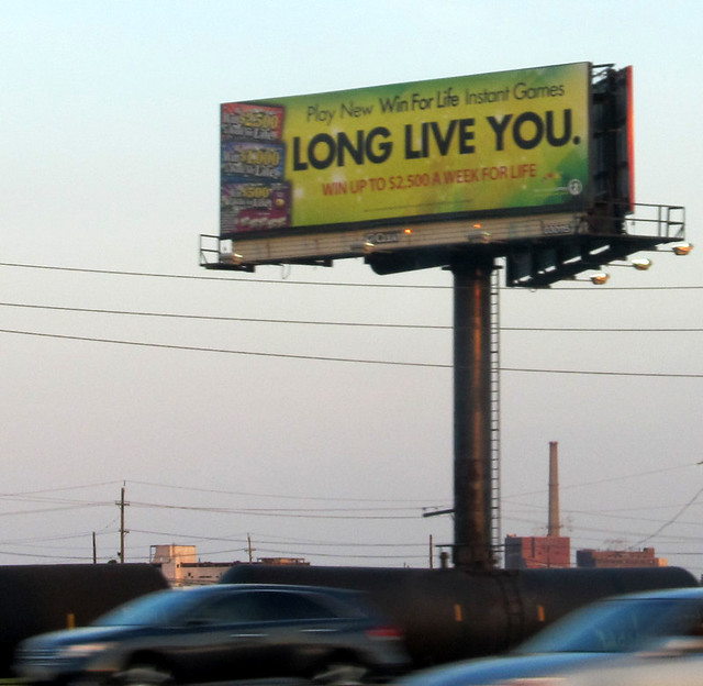 Billboard featuring strange NJ Lottery Win For Life slogan Long Live You.