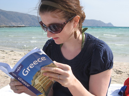 Girl on beach reading Lonely Planet guidebook for Greece