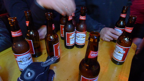 Downward view of Budweiser beer bottles sitting on a wood top table