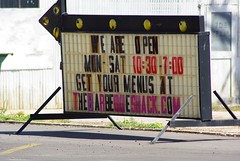 Business sign with hours and a website address. 