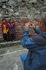 Posing with a smile, Steve D. kneels to photograph children, Tharlam Monastery road, Kathmandu, Nepal