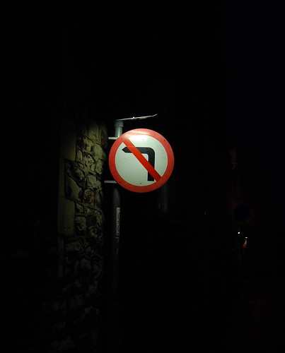 A sign, lit up in the darkness, that reads "No Left Turn".