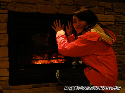 Rachel warming her at an electronic fireplace at the hotel lobby