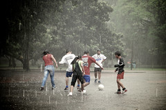 Teenagers playing soccer in the rain