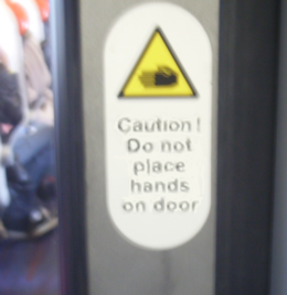 sign on train door reading 'do not place hands on door' (flickr)