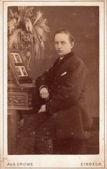 Portrait of a man posing with four portrait photographs by August Crome (c.1880)