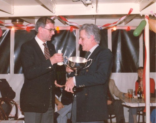 1983 Champion Peter Cabrol receives the Bell & Colvill Trophy from Martin Colvill at a party on the Thames based “Tattershall Castle.